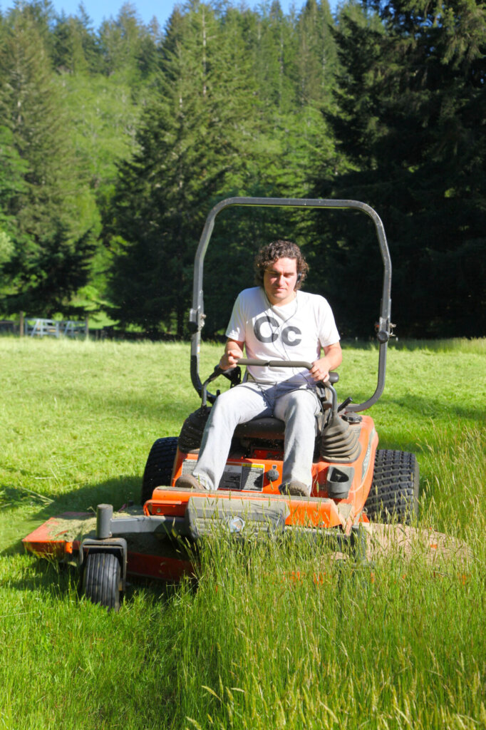 person using a lawnmower to trim grass on a lawn