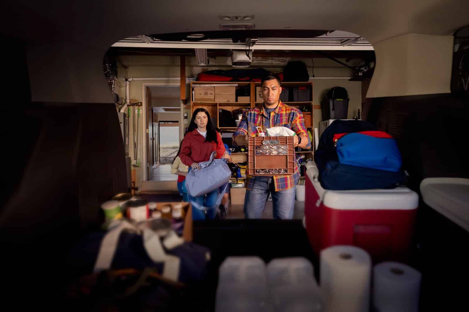 Couple loading trunk of car with emergency supplies